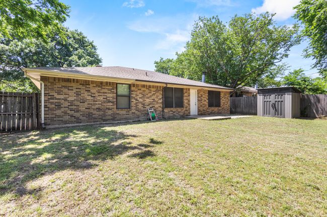 Rear view of house with a storage unit, an outdoor structure, brick siding, and a patio | Image 25