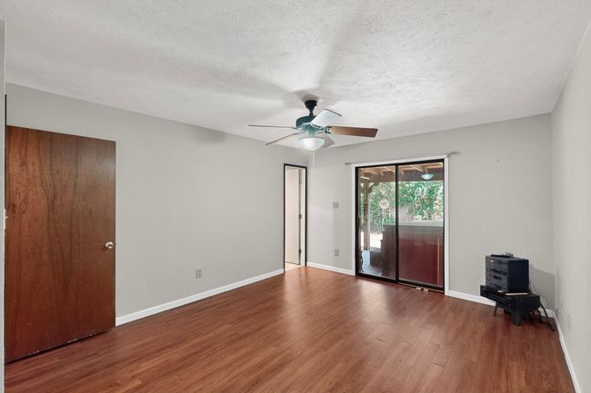 Unfurnished bedroom with access to exterior, a textured ceiling, wood finished floors, and a ceiling fan | Image 10