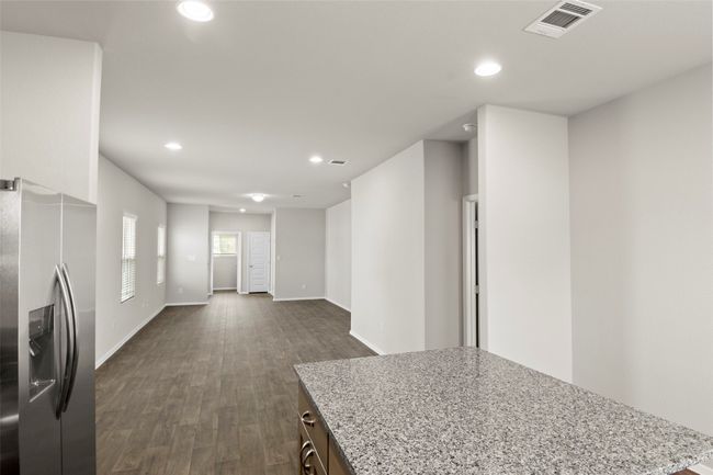 Kitchen featuring recessed lighting, stainless steel fridge with ice dispenser, visible vents, light stone counters, and dark wood-style floors | Image 18