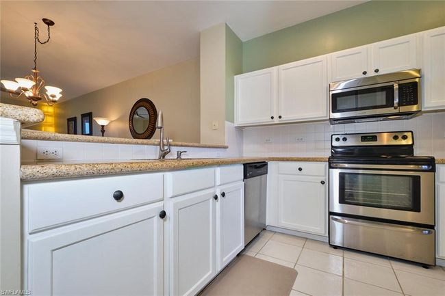 Kitchen featuring white cabinets, a notable chandelier, backsplash, and appliances with stainless steel finishes | Image 15
