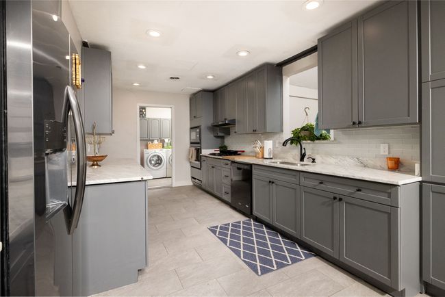 Kitchen featuring washer / clothes dryer, stainless steel fridge, dishwasher, a sink, and gray cabinetry | Image 13