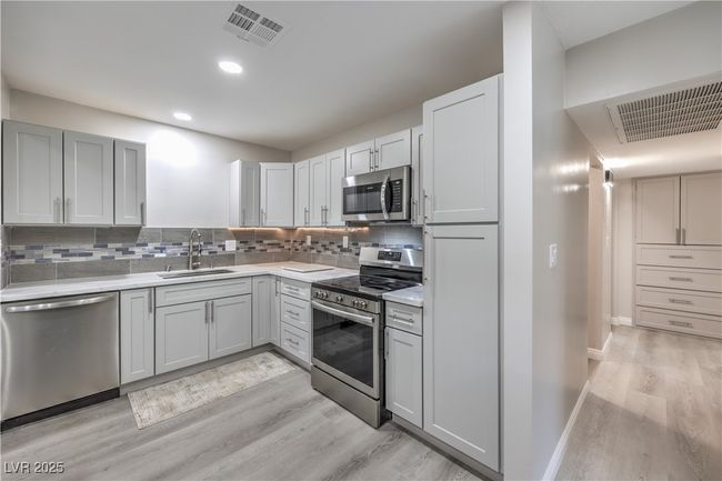 Kitchen with stainless steel appliances, backsplash, a sink, and visible vents | Image 15