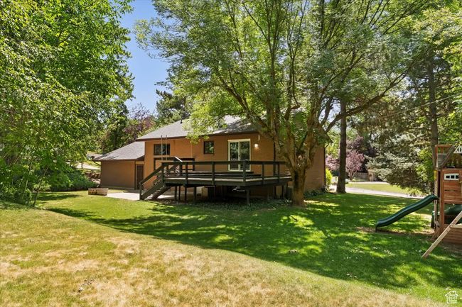 View of grassy yard with a playground, a wooden deck, and stairs | Image 64