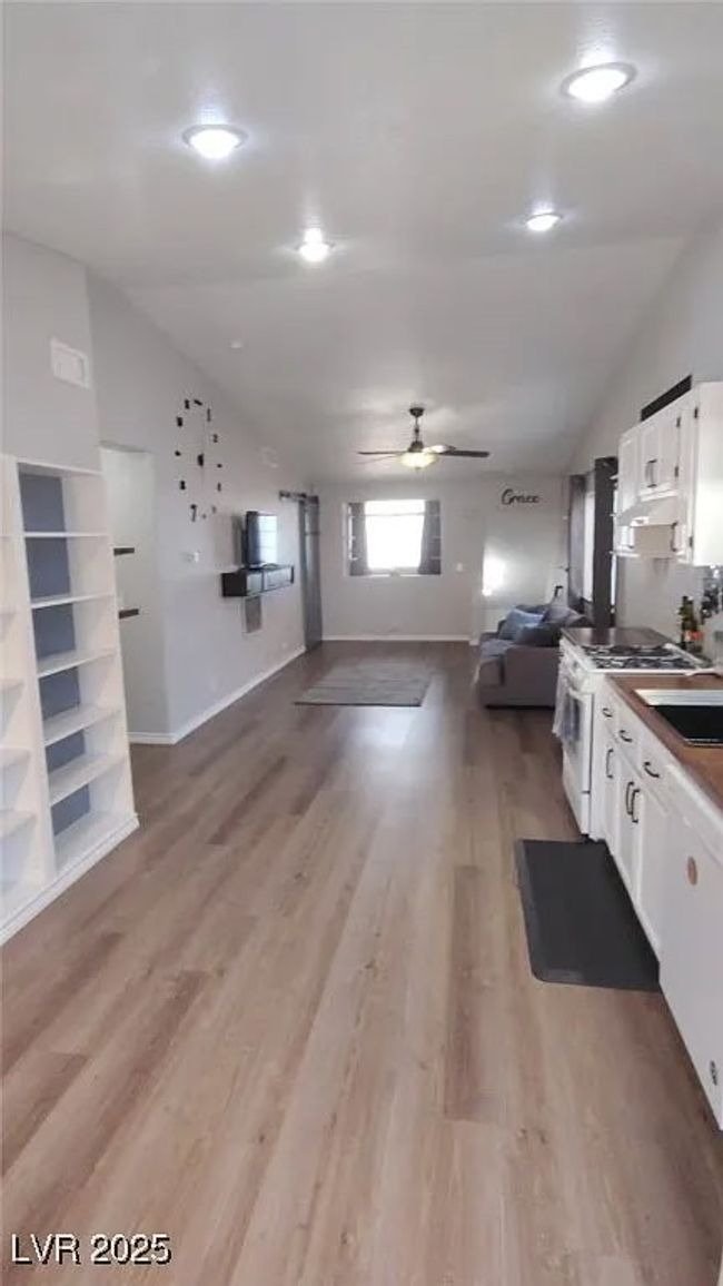 Kitchen featuring open floor plan, white cabinets, white gas range, vaulted ceiling, and light wood-style flooring | Image 11