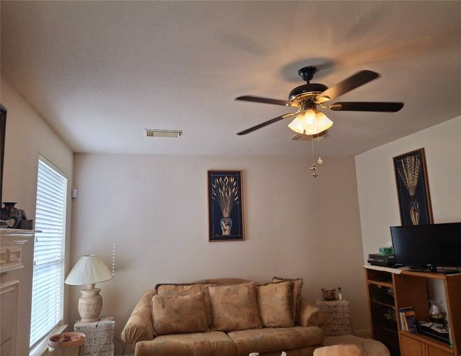 Family room open to kitchen featuring a ceiling fan and fireplace. | Image 6