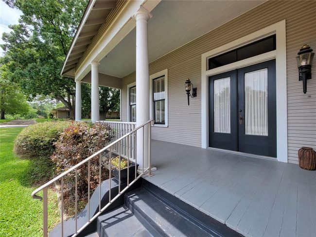 Charming large front porch with elegant white columns and welcoming double glass doors featuring transoms. | Image 5