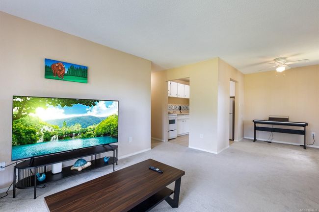 Living area with light carpet, baseboards, and a ceiling fan | Image 11