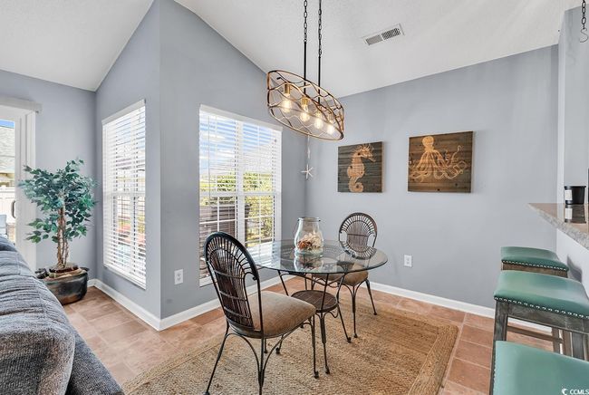 Dining space with vaulted ceiling and light tile patterned floors | Image 10