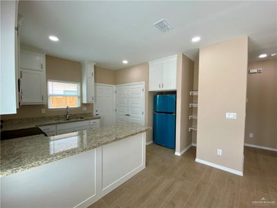 Apt. #1 Kitchen with a wealth of natural light, white cabinetry, kitchen peninsula, and stainless steel appliances | Image 3