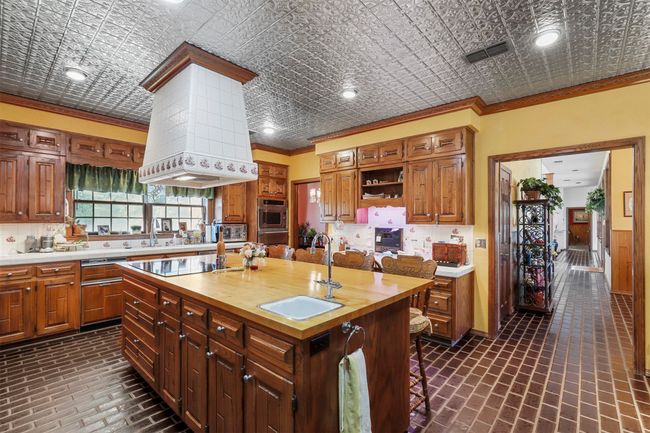 Kitchen with sink, an island with sink, butcher block counters, cooktop, and crown molding | Image 13