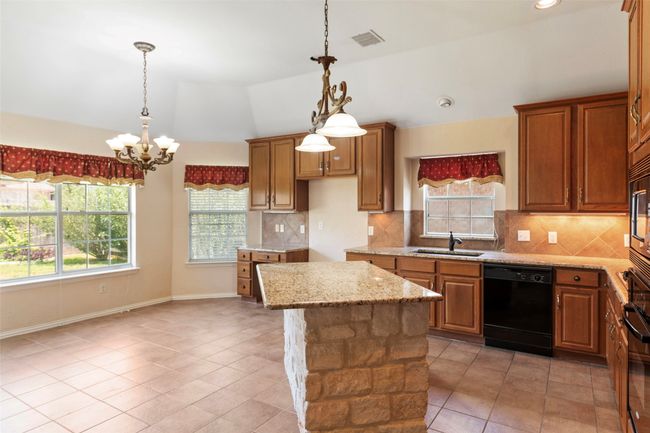 Kitchen featuring dishwasher, a sink, vaulted ceiling, light tile patterned floors, and a chandelier | Image 26