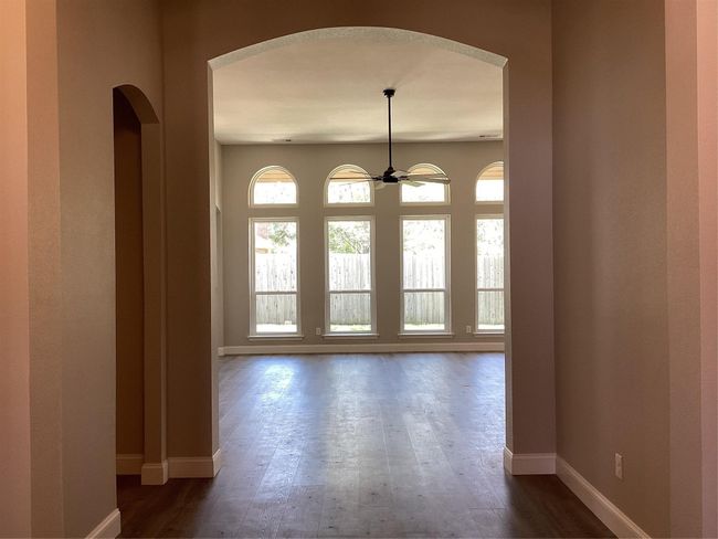 Empty room with arched walkways and dark wood-style floors | Image 5