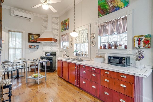 Kitchen features hardwood floors, East Exit door to enjoy wrap around porch and courtyard, windows for great light | Image 13