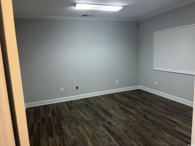 Spare room featuring dark wood-type flooring and crown molding | Image 5