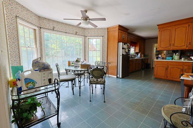 Dining space featuring wallpapered walls, a ceiling fan, and dark tile patterned floors | Image 5