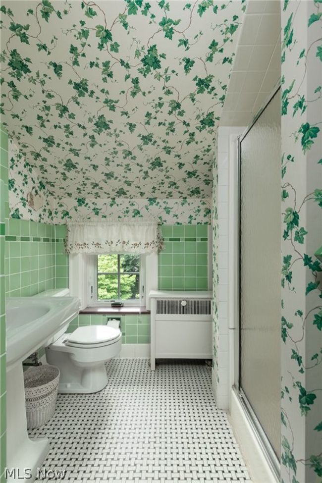 Bathroom featuring radiator, tile floors, a shower with shower door, tile walls, and toilet | Image 34