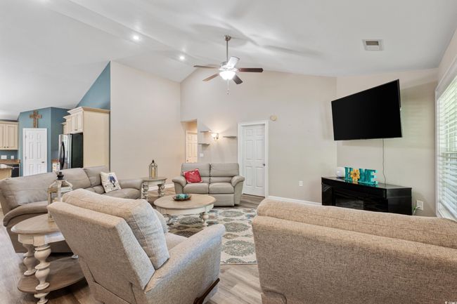 Living room with light wood finished floors, a ceiling fan, and high vaulted ceiling | Image 9