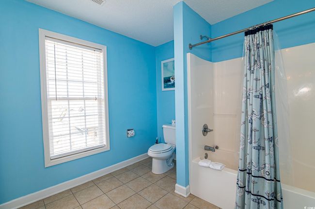 Bathroom featuring shower / bathtub combination with curtain, baseboards, tile patterned floors, and toilet | Image 38