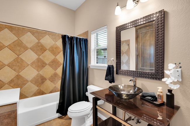 Bath in 2nd downstairs bedroom featuring shower tile, patterned floors, and custom sink | Image 22
