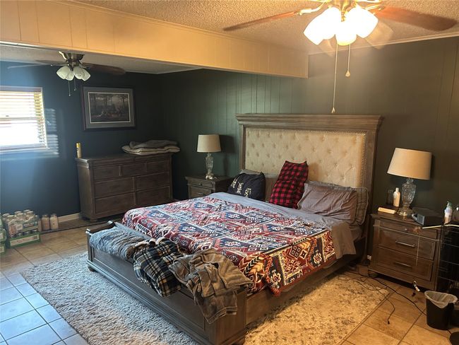 Bedroom featuring light tile patterned flooring, a textured ceiling, and a ceiling fan | Image 6
