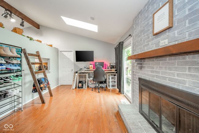 office area with a skylight, light wood-type flooring, and a brick fireplace | Image 13