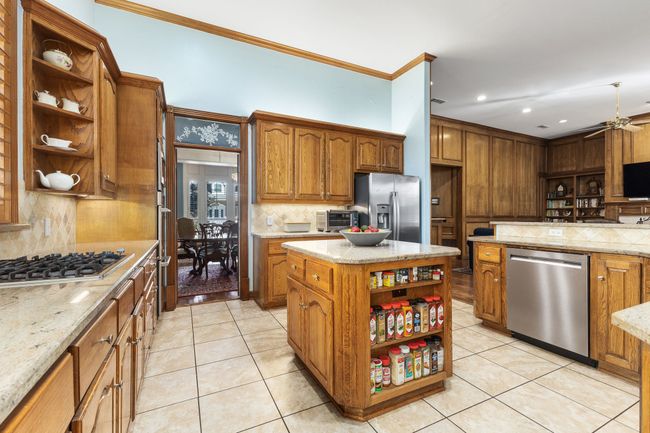 Kitchen featuring light tile patterned floors, open shelves, appliances with stainless steel finishes, and cabinetry | Image 7