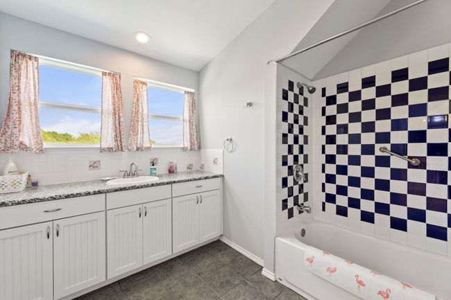 Full bath with tile patterned floors, vanity, shower / washtub combination, lofted ceiling, and backsplash | Image 21
