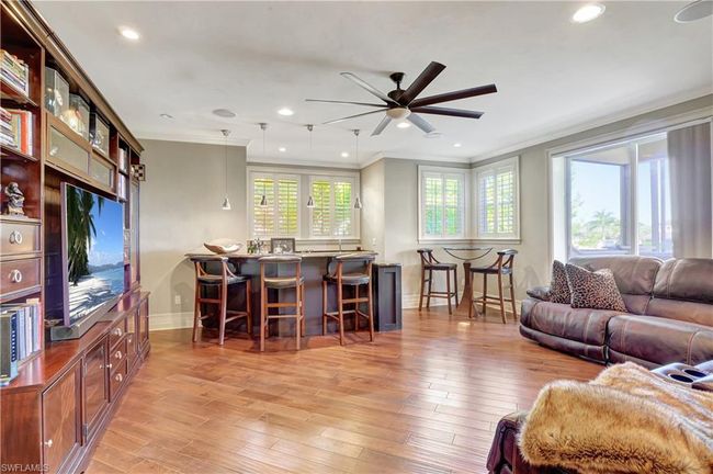 Living room featuring light wood-style floors, a ceiling fan, ornamental molding, and baseboards | Image 13
