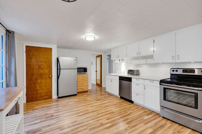 Kitchen featuring light wood finished floors, a sink, appliances with stainless steel finishes, and decorative backsplash | Image 26
