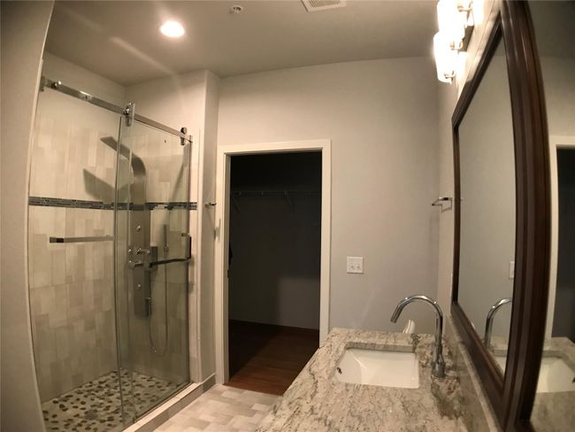 Bathroom featuring a stall shower, wood finished floors, a walk in closet, vanity, and recessed lighting | Image 13
