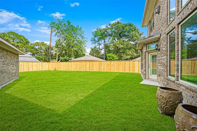 Expansive backyard with fresh landscaping and plenty of space for a pool or play area. The clean fencing, mature trees, and large windows create an inviting and private outdoor retreat. | Image 42
