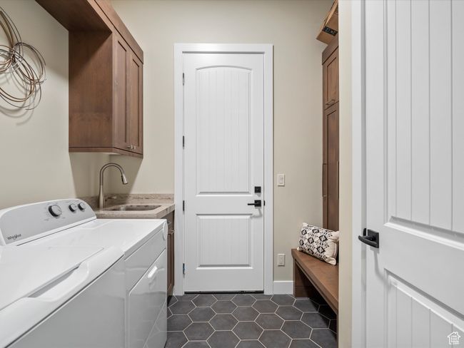 Washroom featuring cabinet space, washer and dryer, dark tile patterned flooring, and baseboards | Image 28