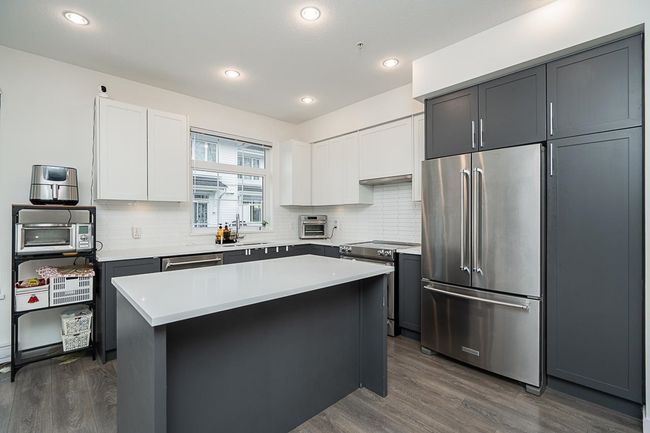 Kitchen featuring backsplash, appliances with stainless steel finishes, dark wood-type flooring, a sink, and a kitchen island | Image 11