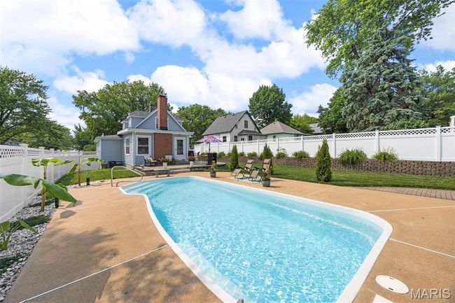 View of swimming pool with a patio area and a fenced backyard | Image 39