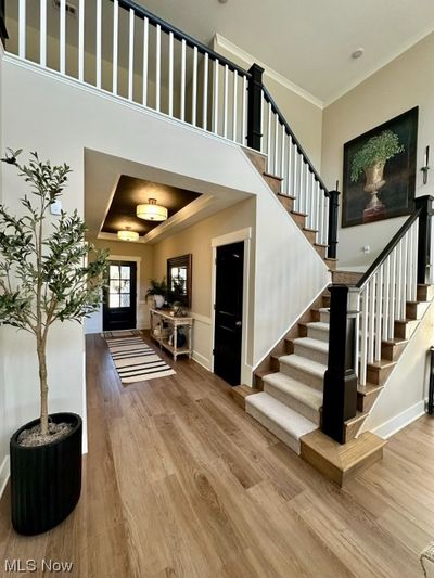 Foyer with hardwood / wood-style floors, crown molding, a high ceiling, and a raised ceiling | Image 3