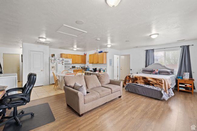 Bedroom with attic access, visible vents, light wood finished floors, and white fridge with ice dispenser | Image 42