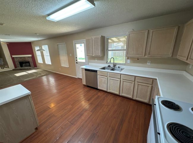 Kitchen with dishwasher, stove, a fireplace, sink, and dark hardwood / wood-style flooring | Image 6