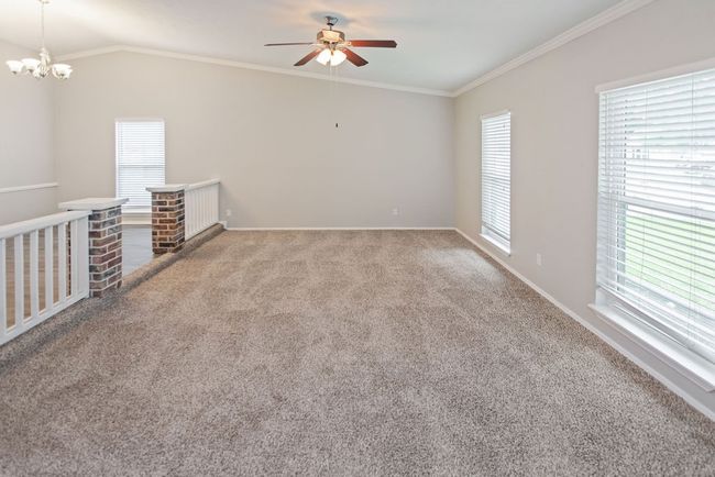 Unfurnished room featuring carpet floors, vaulted ceiling, ornamental molding, a ceiling fan, and a chandelier | Image 15
