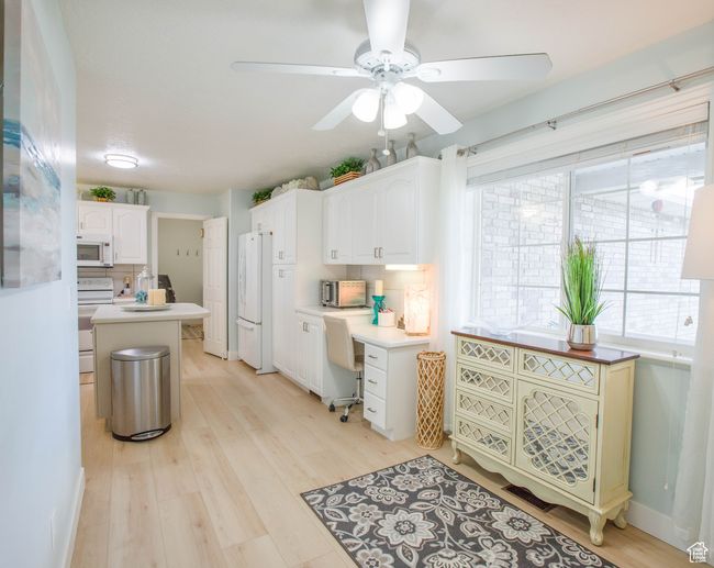 Kitchen with white appliances, ceiling fan, light wood-style flooring, white cabinetry, and light countertops | Image 31