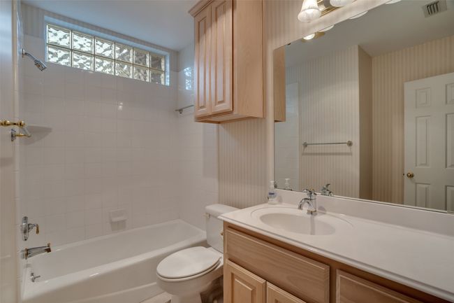 Bathroom with wallpapered walls, toilet, vanity, and shower combination | Image 25