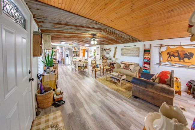 Living room with ceiling fan, wooden ceiling, vaulted ceiling, and light wood-type flooring | Image 16