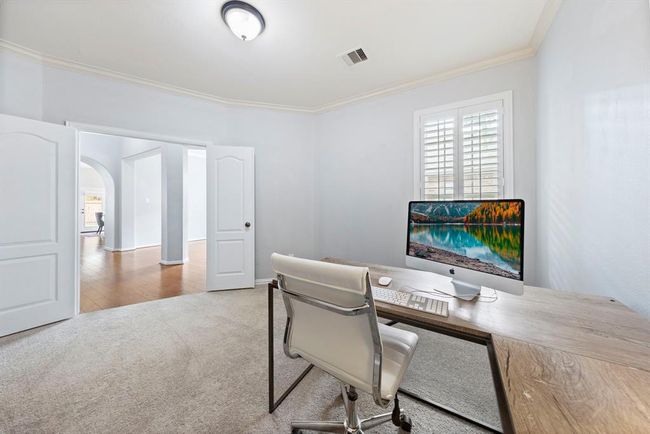 Just off the entry, double doors lead to a bright home office with plantation shutters and plush carpet—ideal for work or study. | Image 5