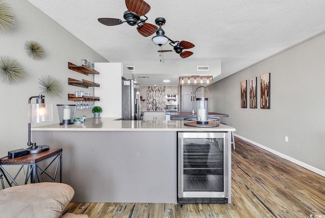 Kitchen featuring a ceiling fan, open shelves, freestanding refrigerator, beverage cooler, and visible vents | Image 23