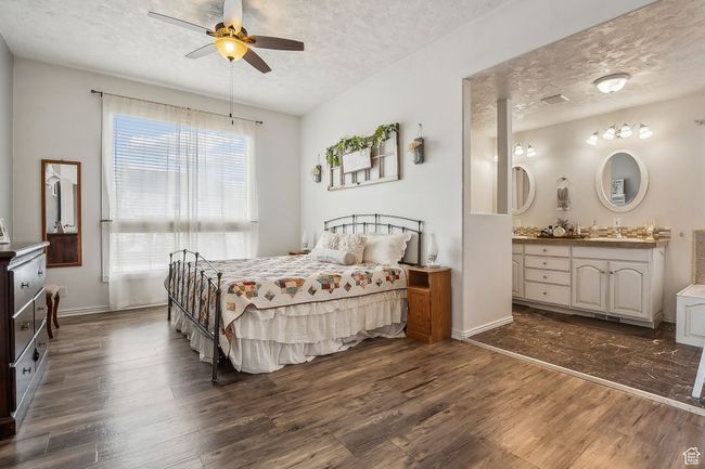 Bedroom with baseboards, a ceiling fan, dark wood-type flooring, and a textured ceiling | Image 20