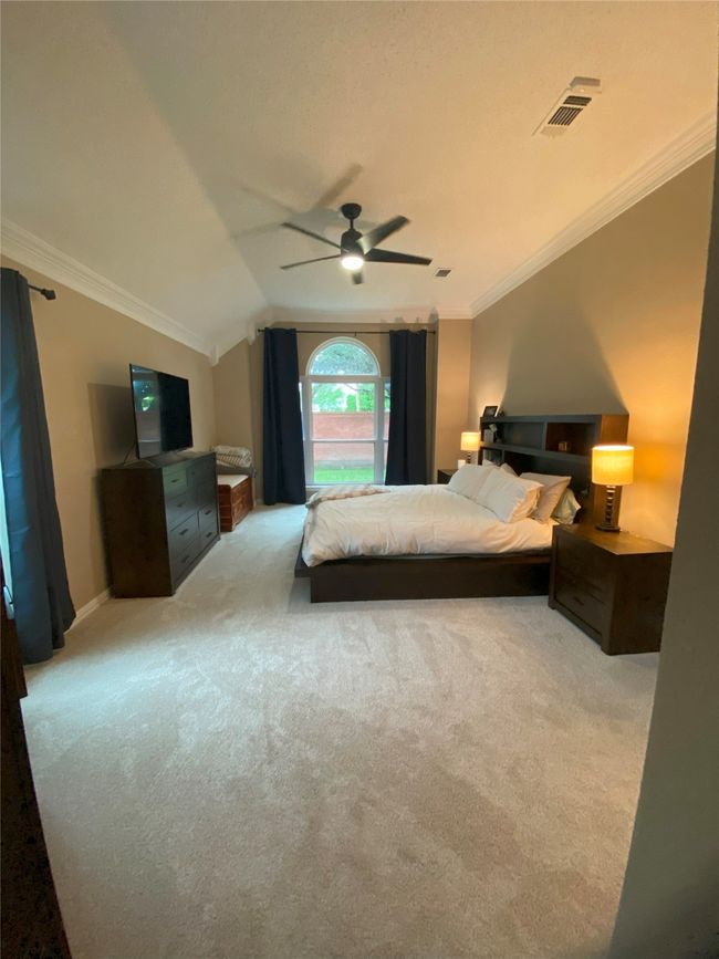 Bedroom with a ceiling fan, ornamental molding, visible vents, vaulted ceiling, and light carpet | Image 18