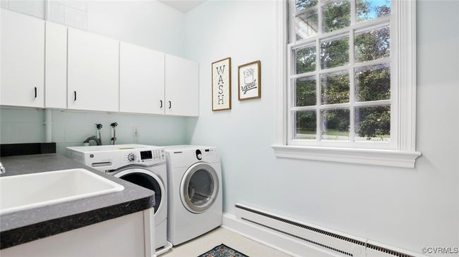 Laundry room featuring a baseboard heating unit, cabinet space, washing machine and dryer, and tile patterned flooring | Image 11
