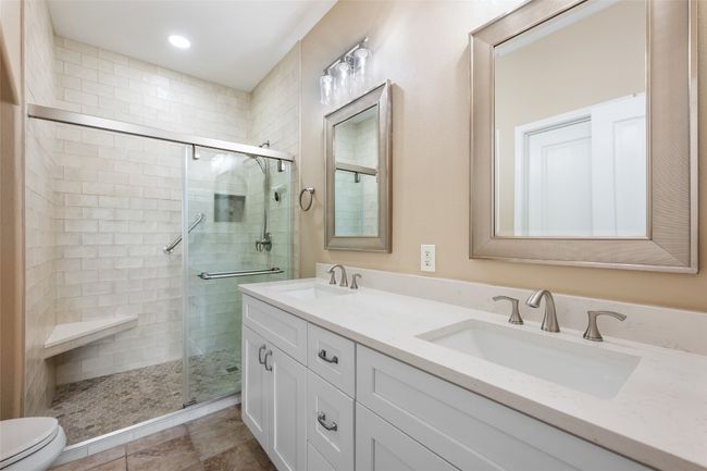 Primary bath with updated quartz double vanity, subway tile shower surround, and seamless glass shower doors. | Image 19