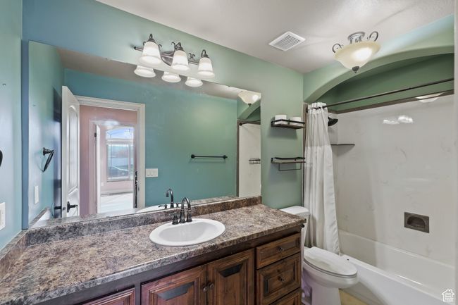 Bathroom with toilet, visible vents, shower / bathtub combination with curtain, and vanity | Image 35