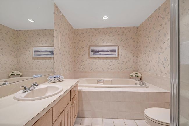 Bathroom featuring vanity, a bath, wallpapered walls, tile patterned flooring, and recessed lighting | Image 13