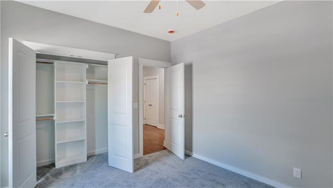 Unfurnished bedroom featuring carpet, baseboards, a closet, and a ceiling fan | Image 13